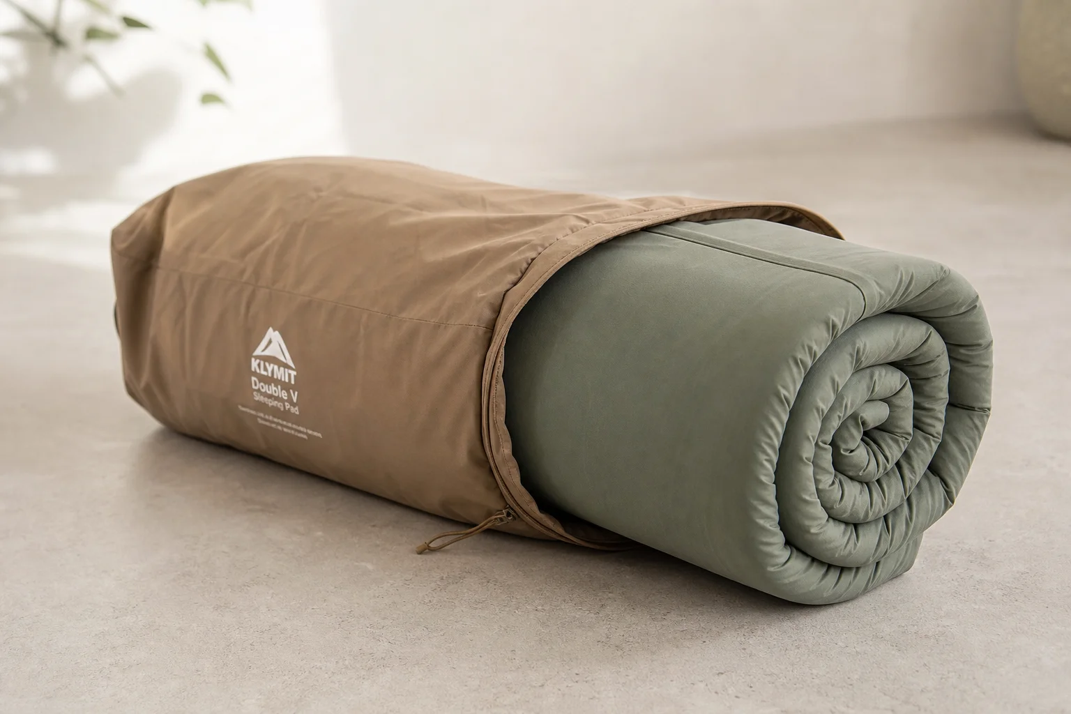 A camping mattress being rolled and packed into its storage bag