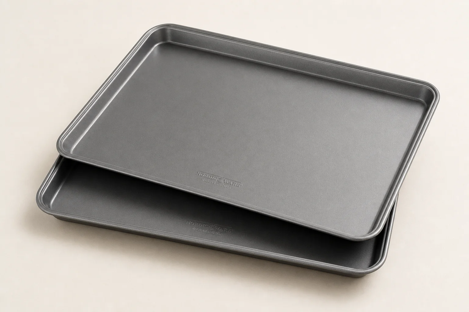 Five different baking sheets and pans arranged on a concrete surface