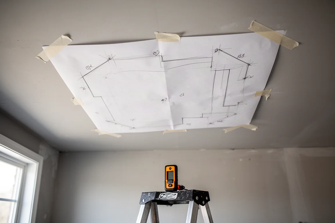 Template di installazione appiattito con nastro adesivo su un soffitto di garage accanto a un cercatore di travi