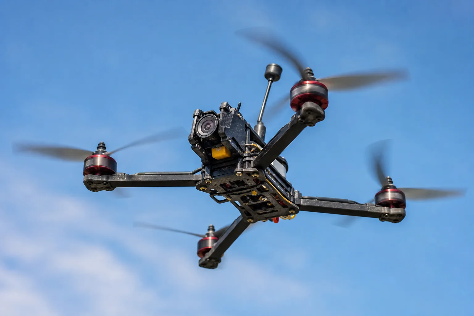FPV racing drone in flight against blue sky with motion blur