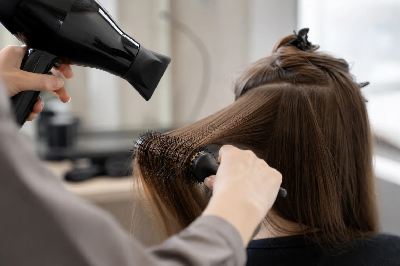 Professioneller Hairstylist beim Föhnen mit Rundbürstentechnik