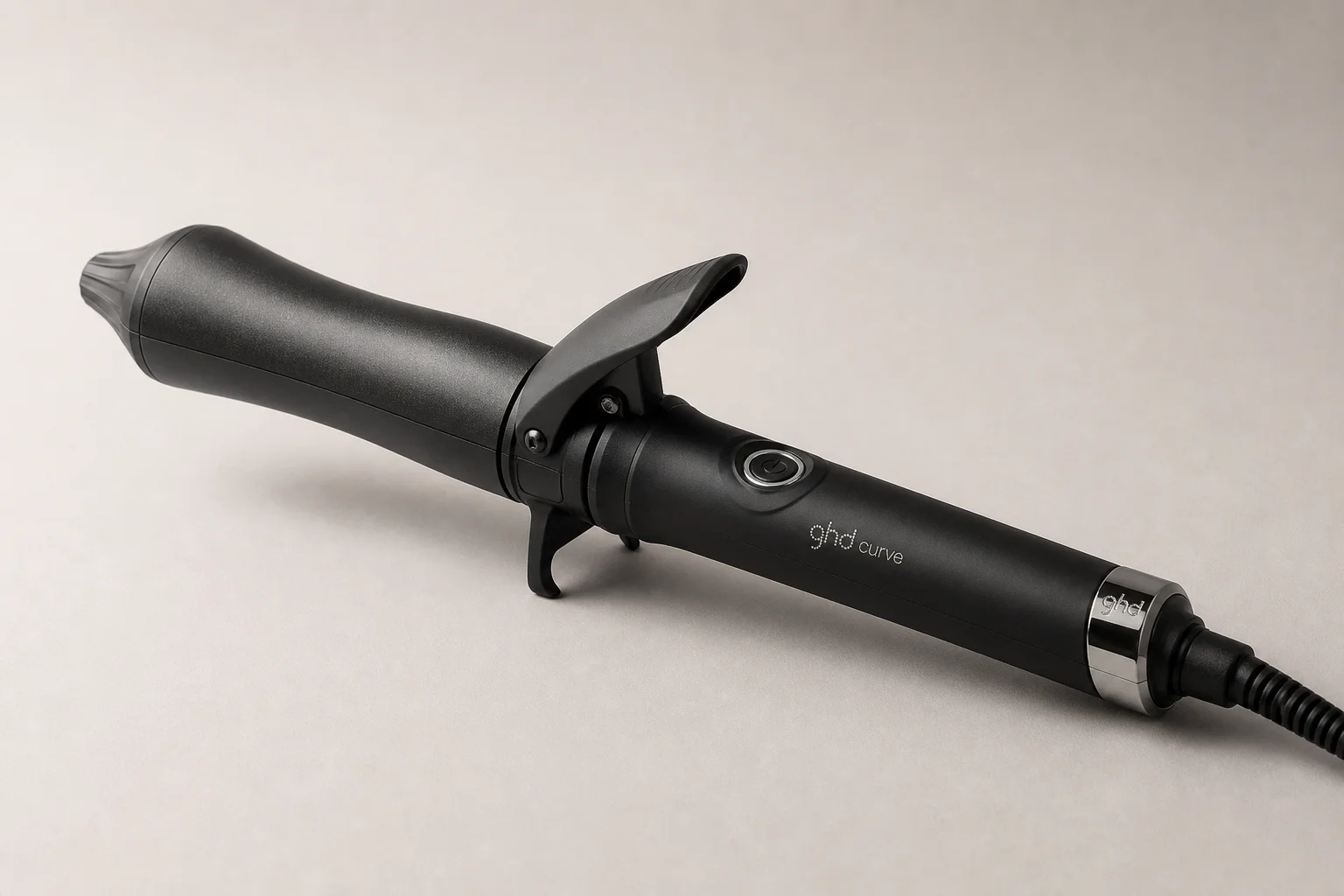 Five curling irons in various sizes arranged on a marble surface