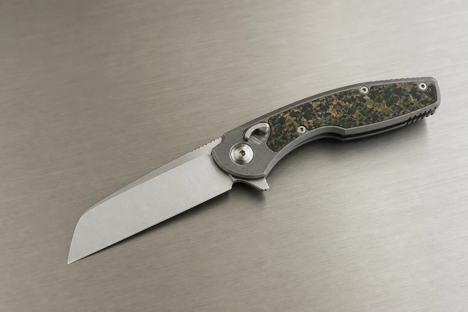 Premium folding knives with titanium handles and Damasteel blades on a dark slate surface