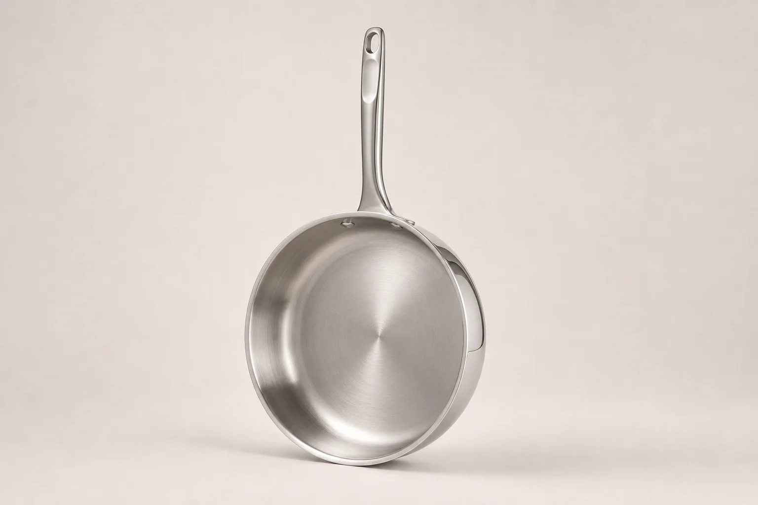 Five stainless steel pans arranged in a fan pattern on concrete surface