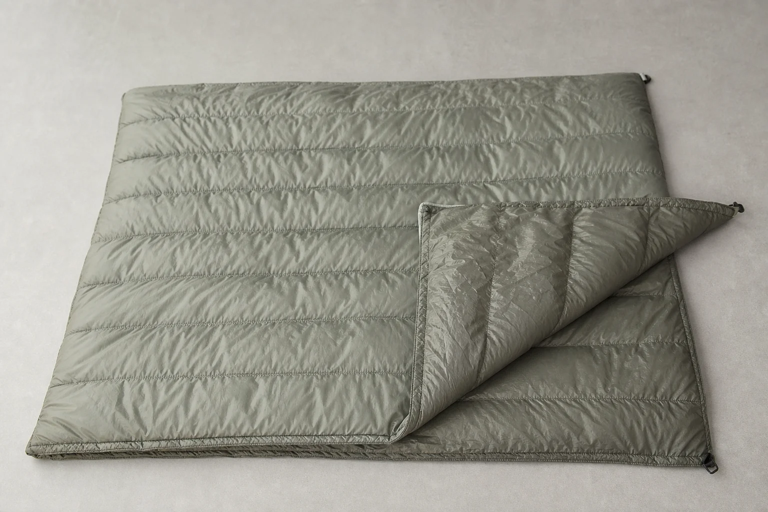 Lightweight sleeping quilt laid flat showing material texture and construction