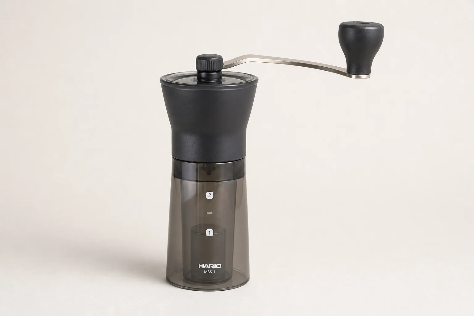 Three hand coffee grinders: Hario Slim, KINGrinder P1, and Comandante arranged on concrete