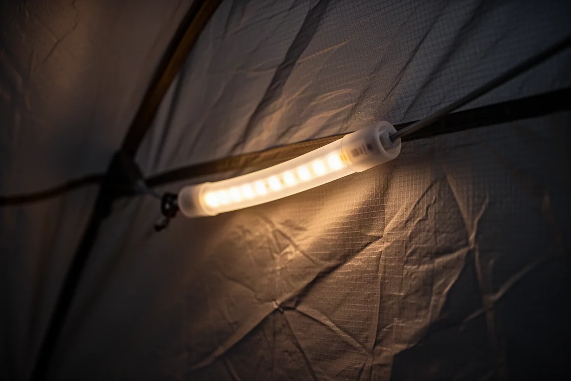 Primer plano de una tira LED con funda de silicona brillando a baja intensidad dentro de una tienda de noche