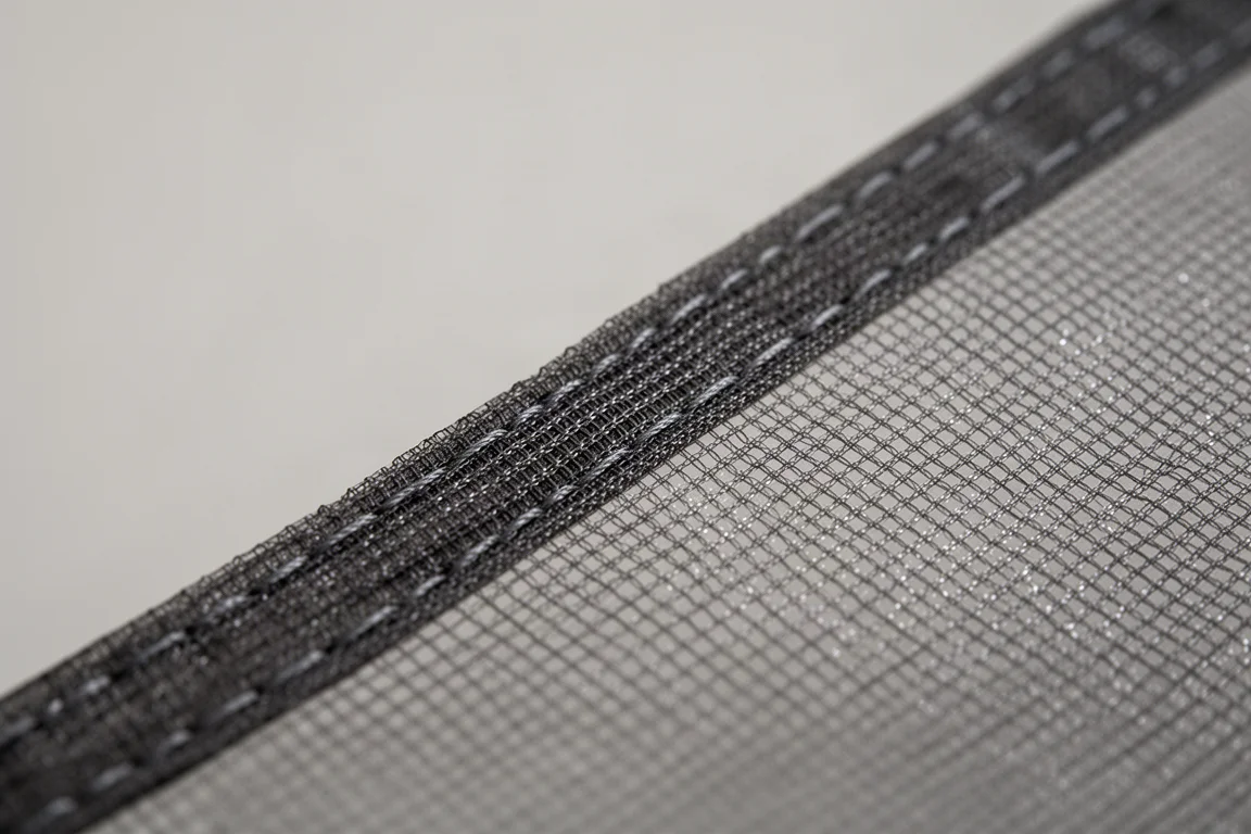 Close-up of dark translucent monofilament mesh fabric with a reinforced double-stitched seam