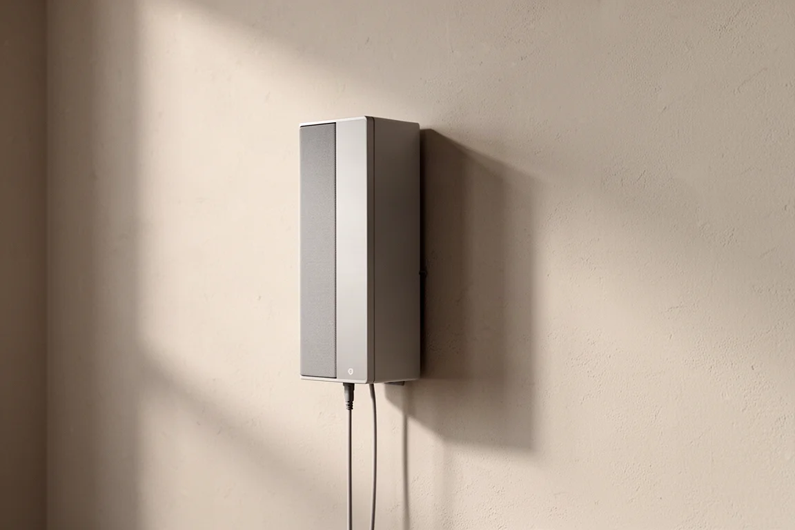 Sidovy av en smal vägghögtalare med kabel som kommer in underifrån i basen