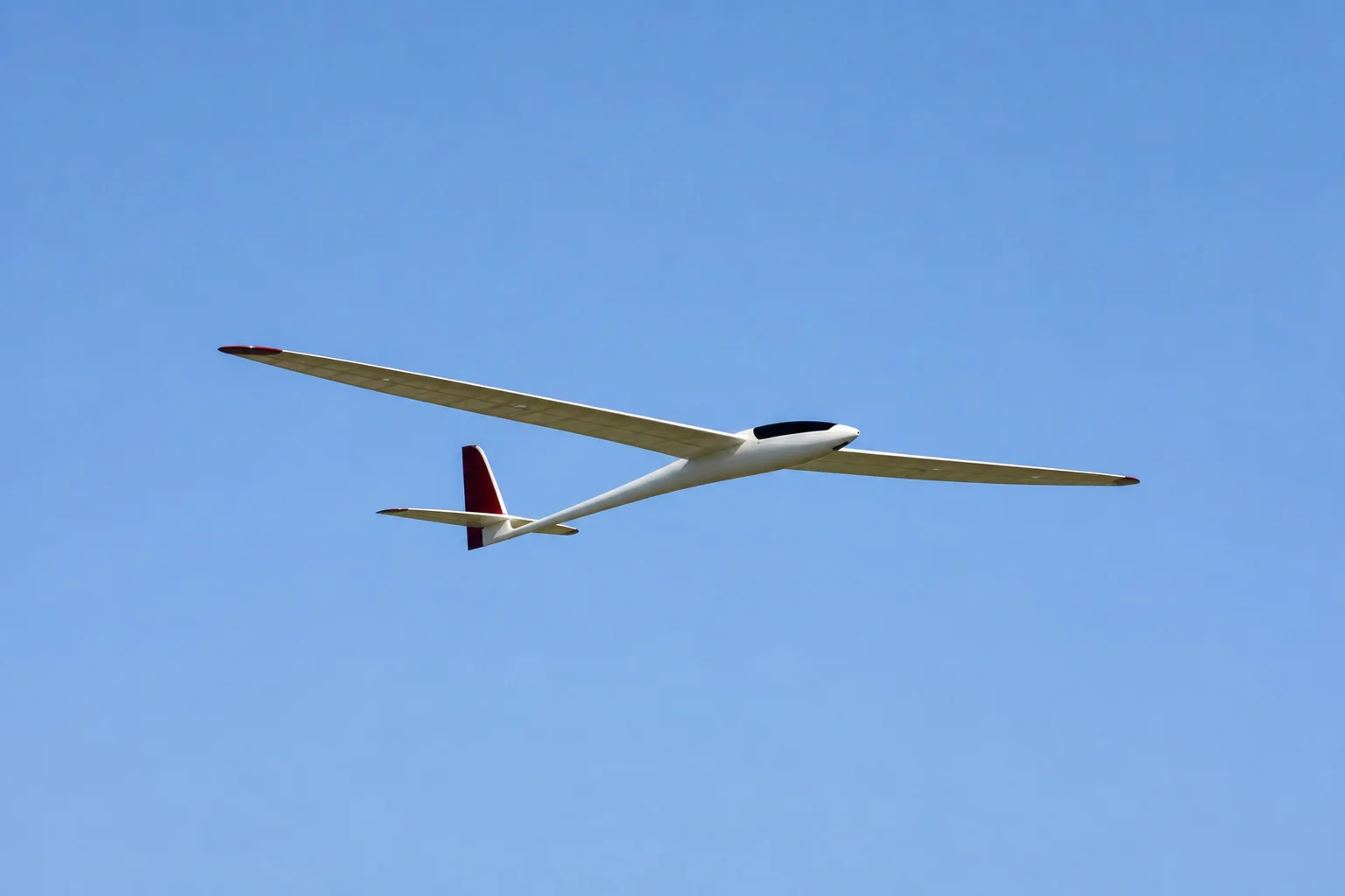 RC glider in flight against blue sky during thermal soaring