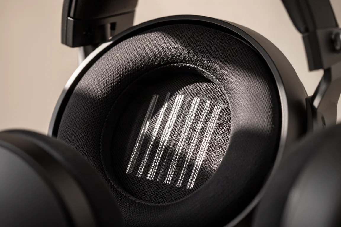 Detalle macro de una rejilla de auriculares abiertos con el driver visible detrás
