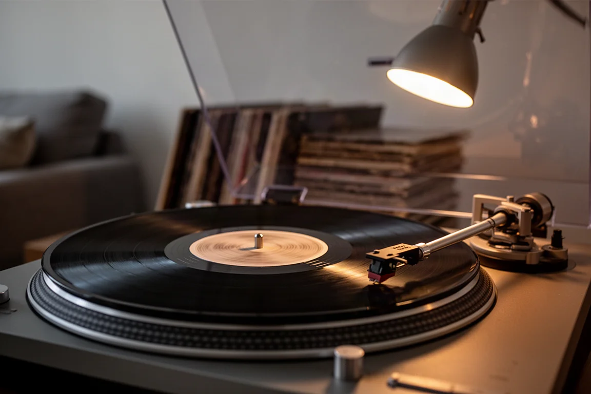 Turntable spinning a vinyl record at dusk with warm lamp light on the platter