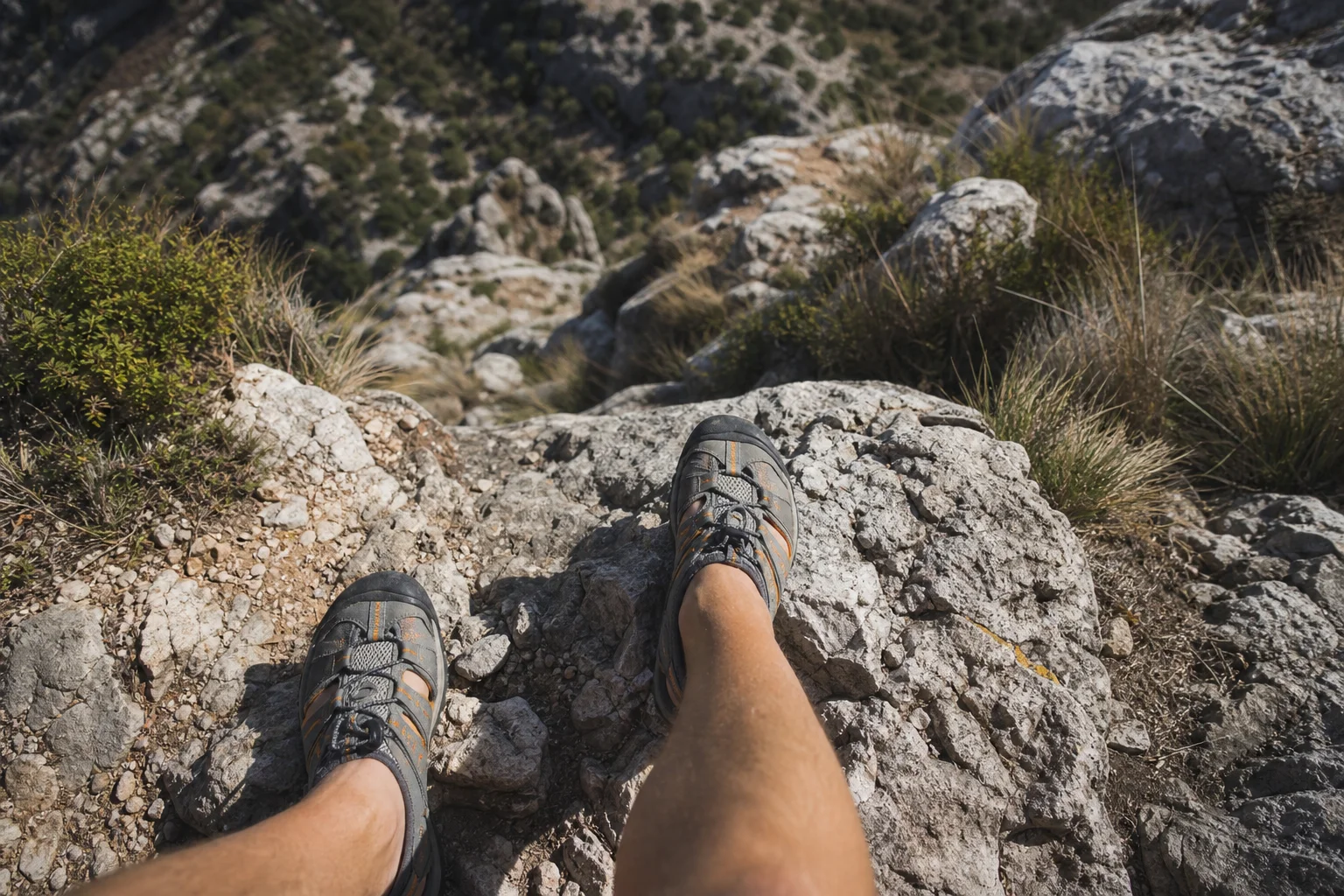 Hiker's feet on rocky mountain terrain during warm weather hike