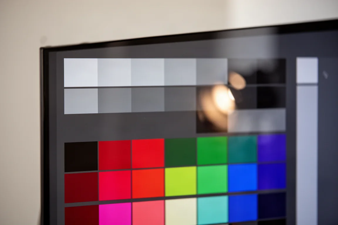 Mire de test colorimétrique composée de gris et de nuances saturées affichée sur un grand écran brillant
