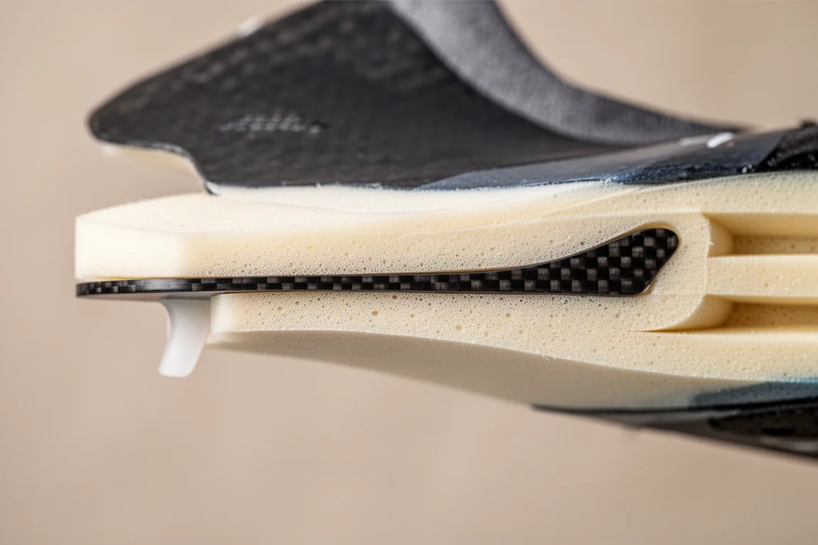 Close-up of a winged carbon plate visible in a cutaway racing shoe midsole