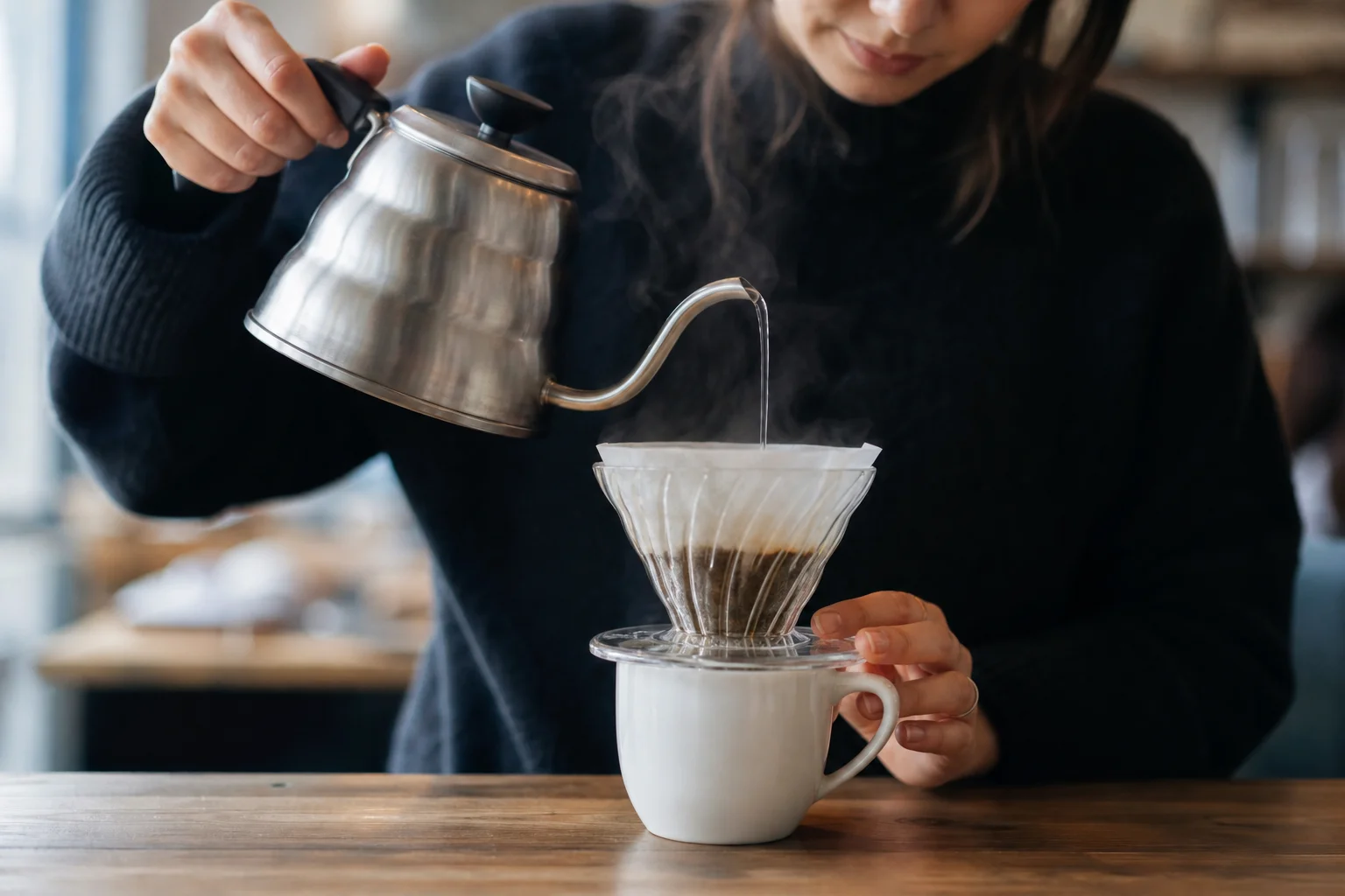 Barista pouring water through V60 dripper into ceramic cup