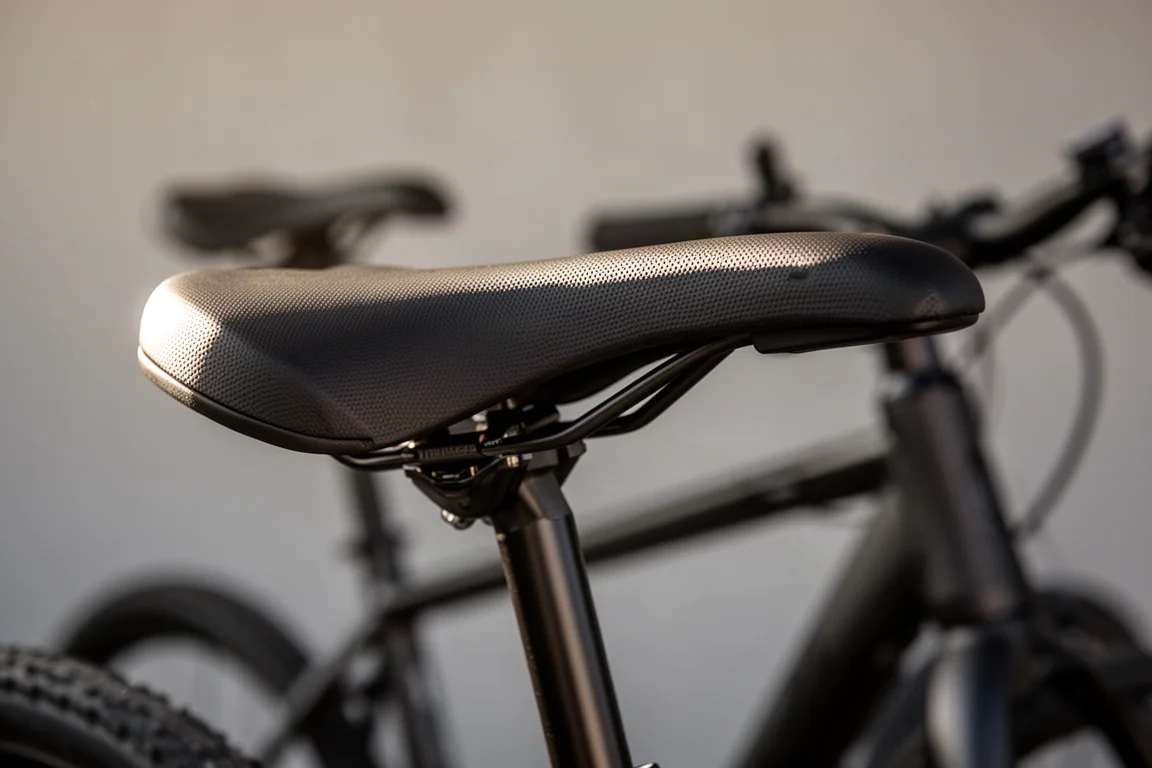 Close-up of a bicycle saddle mounted on a seatpost with its curved profile in raking light