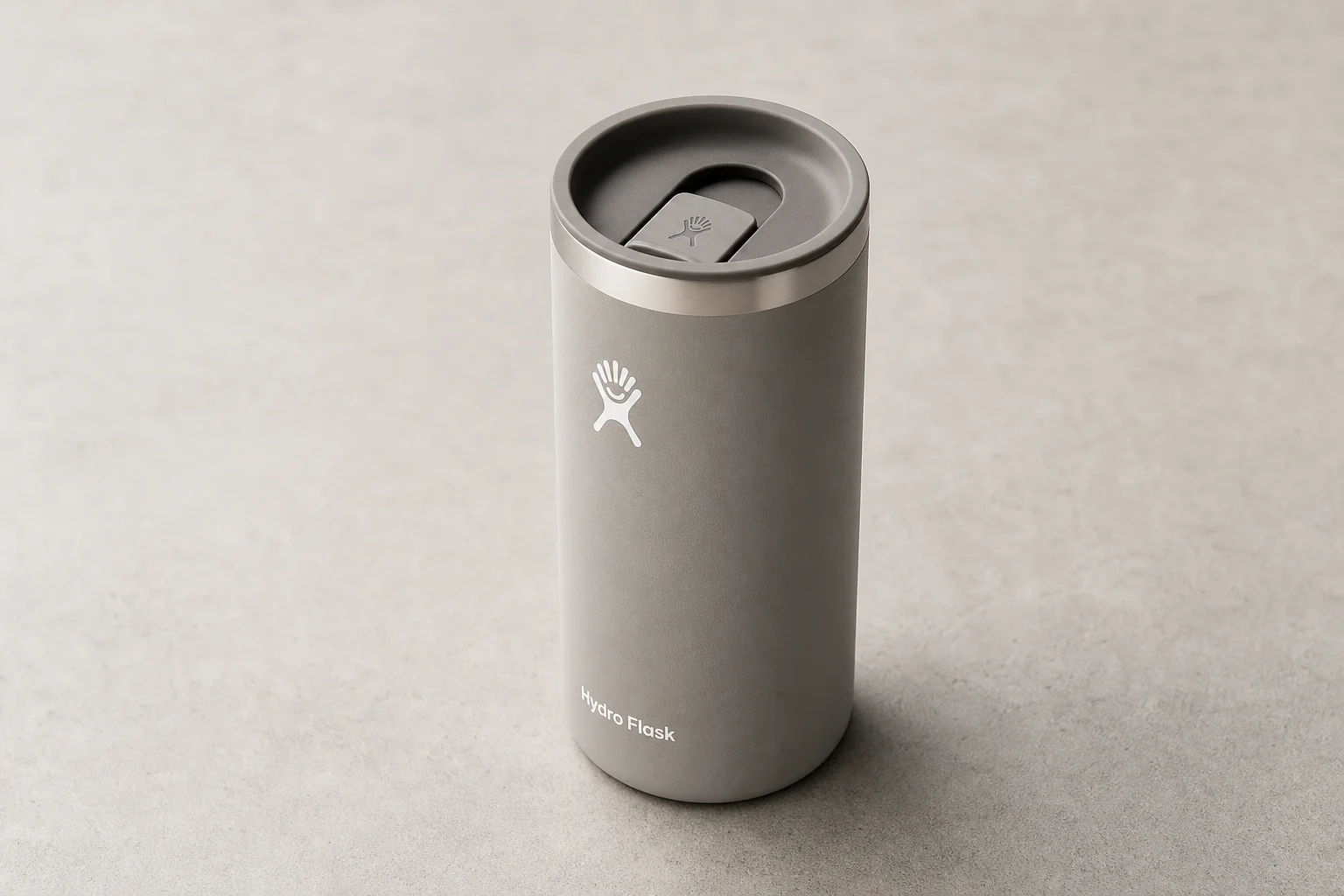 Nine insulated travel mugs arranged on concrete surface in various styles and colors