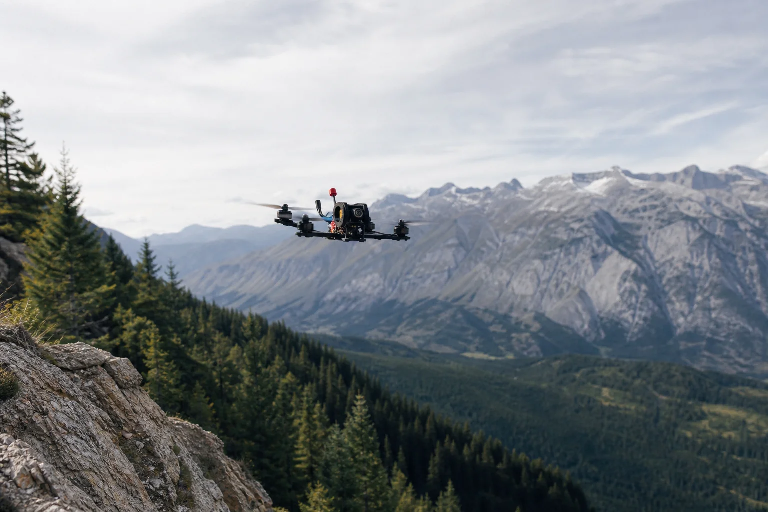 FPV drone in flight over mountainous terrain with forest below