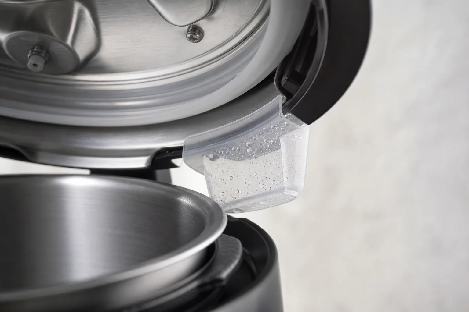 Close-up of pressure cooker lid sealing mechanism with condensation collection cup