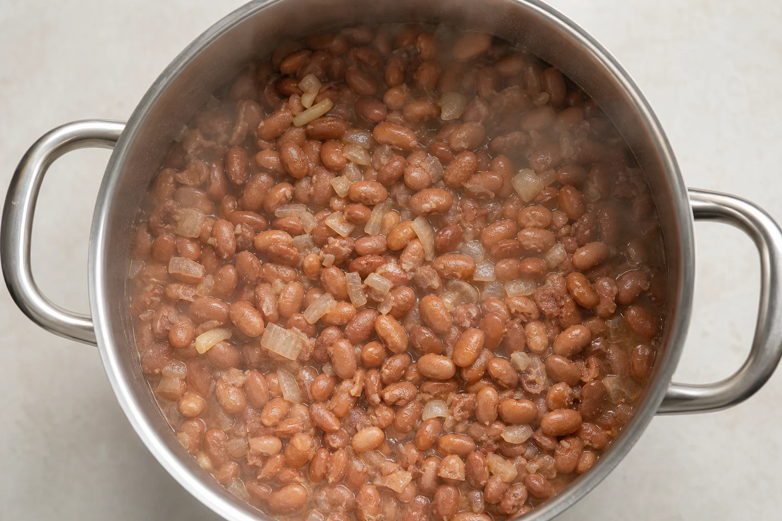 Cooked pinto beans in a multicooker pot with visible texture and aromatics