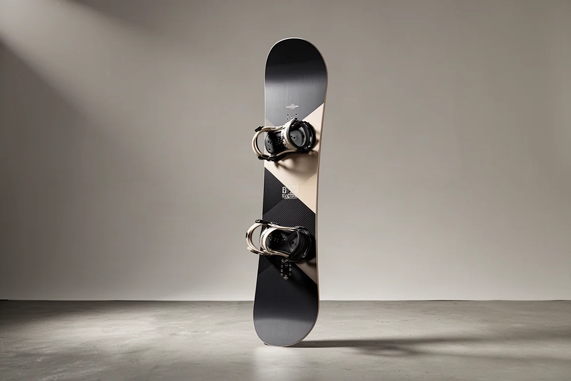 Women's freestyle twin snowboard standing upright on concrete against a grey backdrop