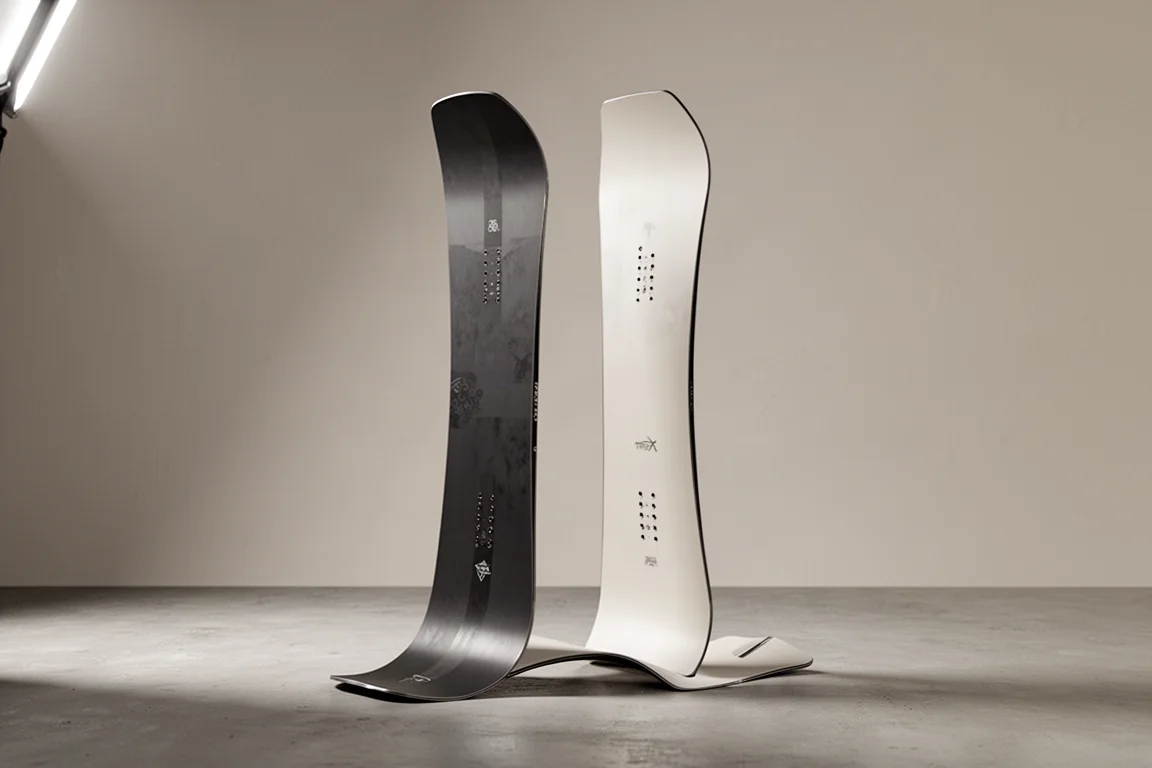 Soft-flexing twin-tip freestyle snowboard standing upright on a matte concrete surface