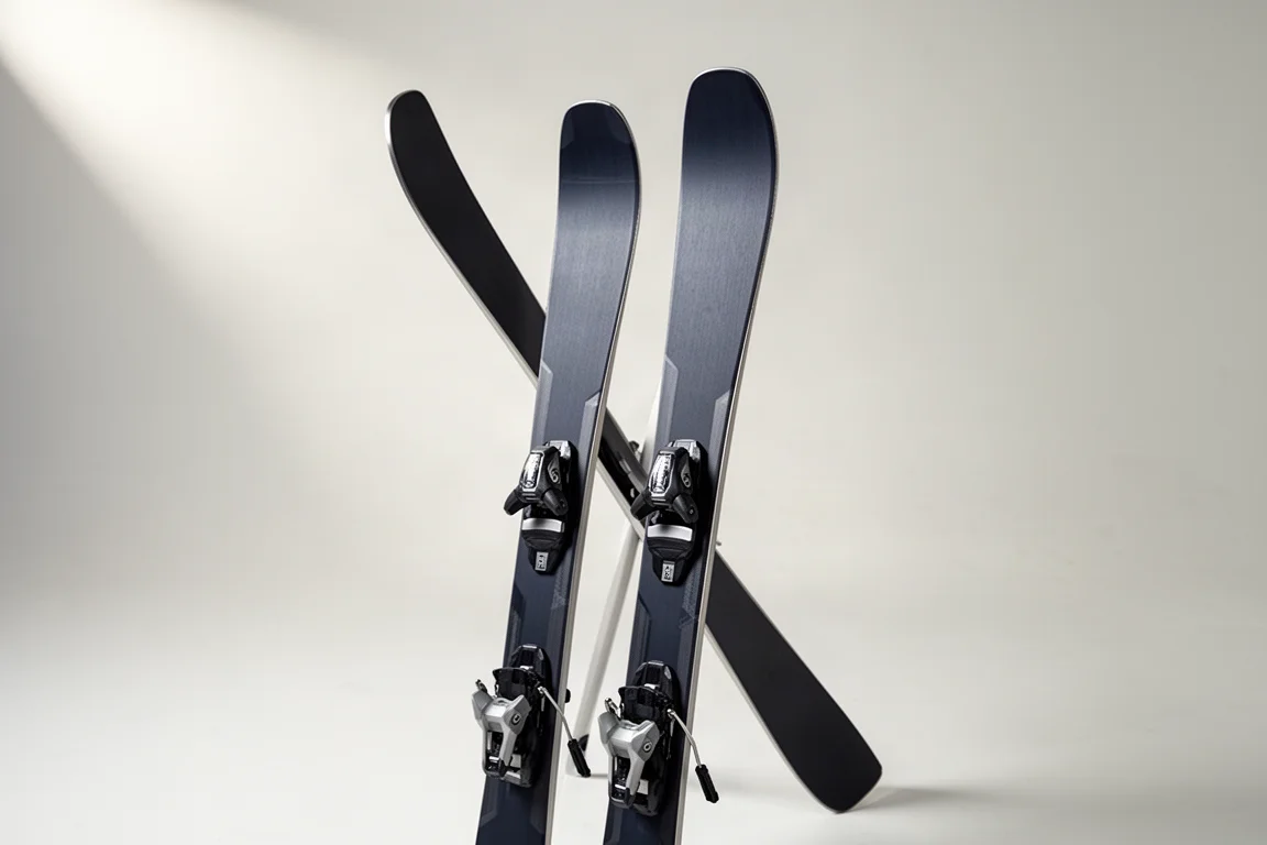 Paar Frontside-Carving-Skier aufrecht stehend vor einem hellgrauen, nahtlosen Hintergrund