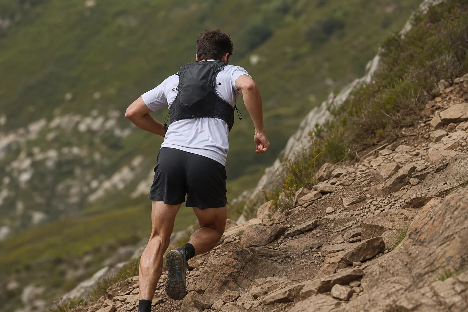 Trailrunner bei einem steilen Anstieg mit während der Anstrengung gesicherter Laufweste
