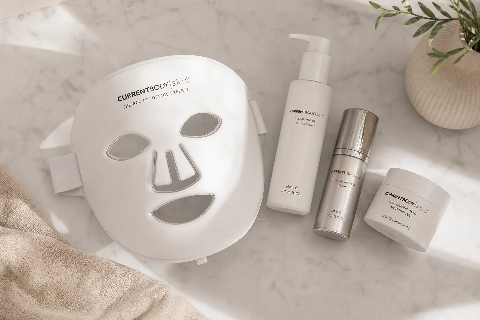 Skincare routine setup with LED mask and beauty products on marble