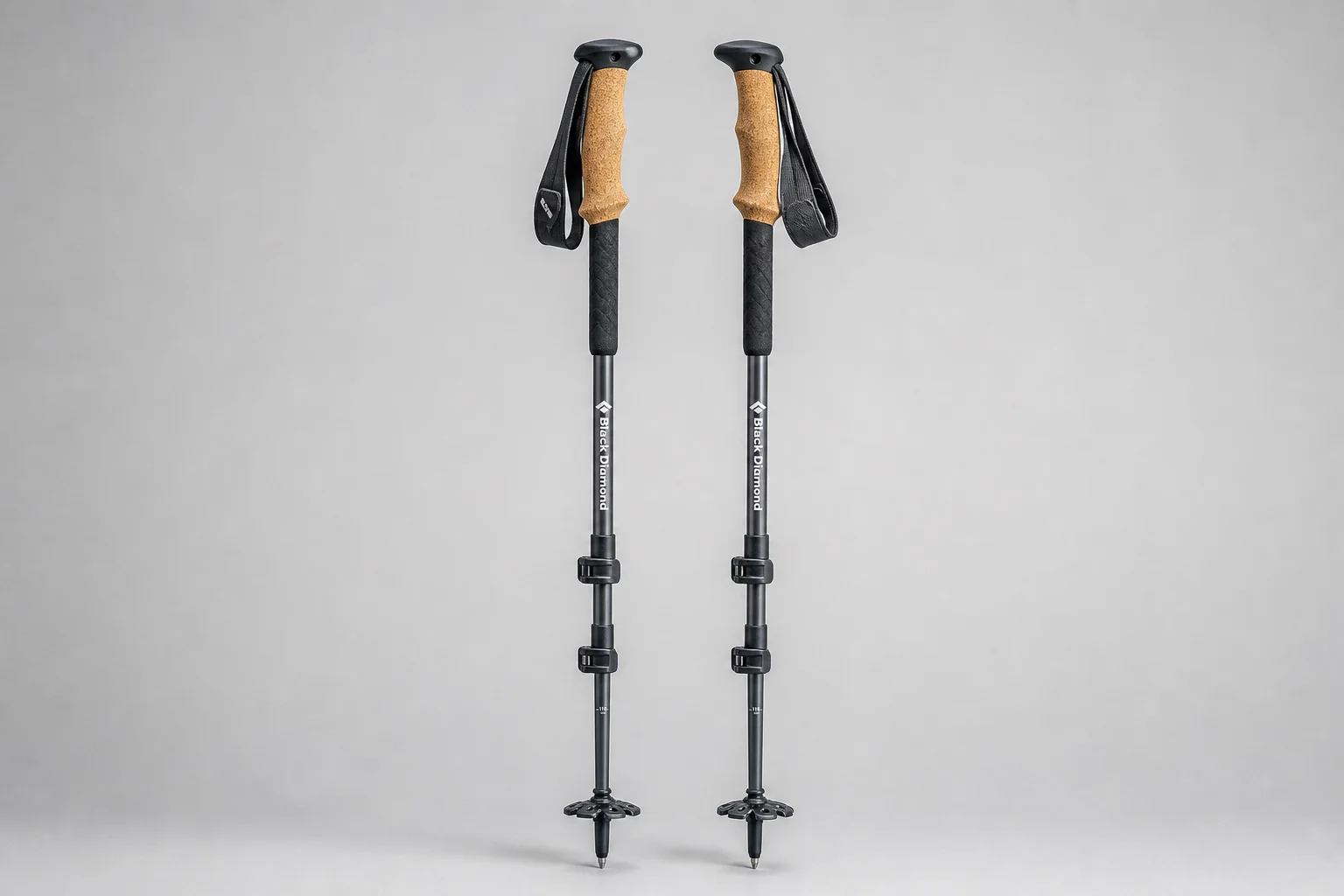 Five trekking poles and one hiking staff arranged on neutral backdrop