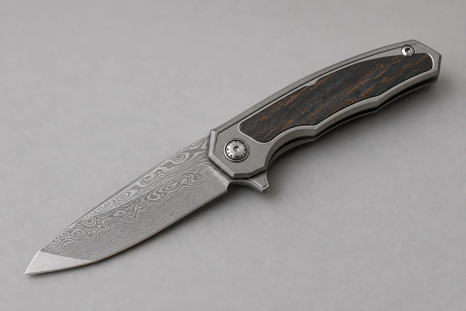 Premium folding knives with titanium handles and Damasteel blades on a dark slate surface