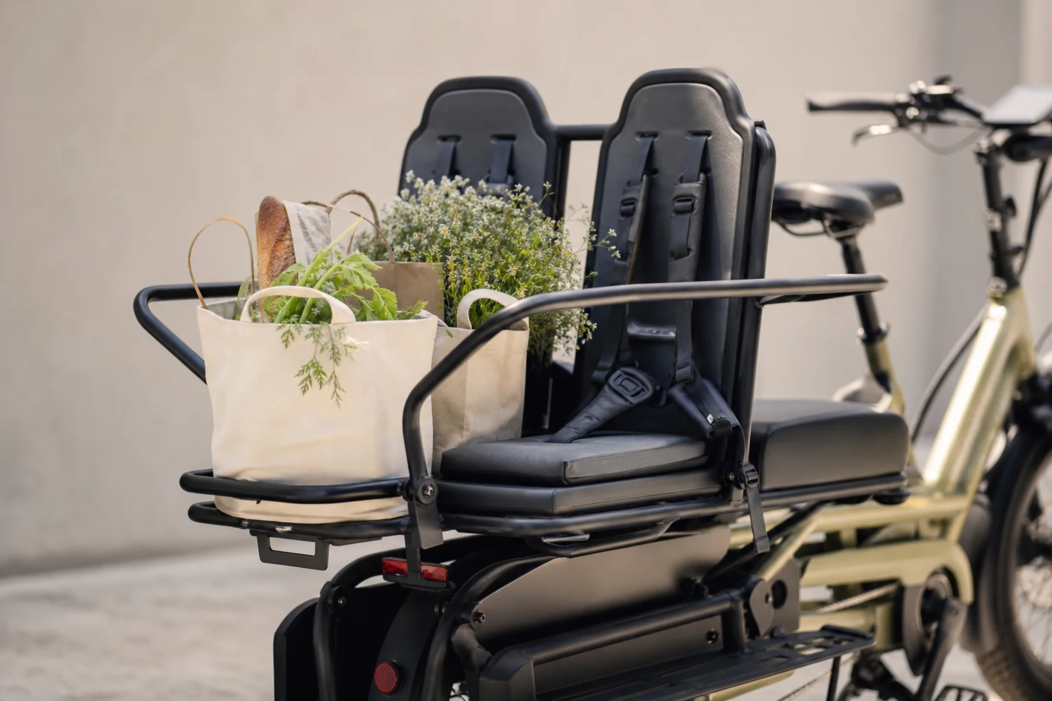 Primo piano dei portapacchi e seggiolini per bambini su una e-cargo bike carica di borse della spesa