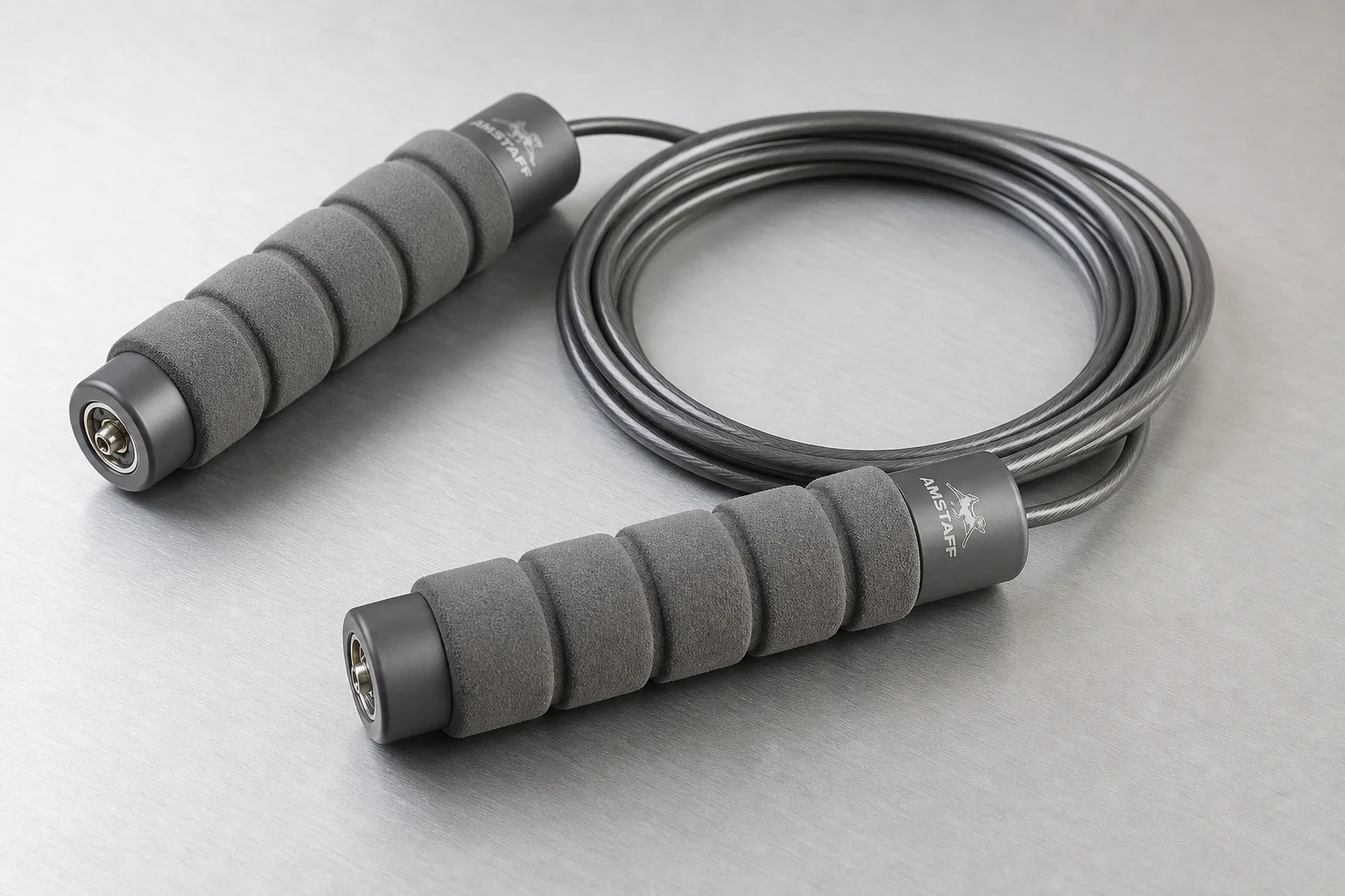 Five jump ropes with different handle styles and cable designs arranged on concrete