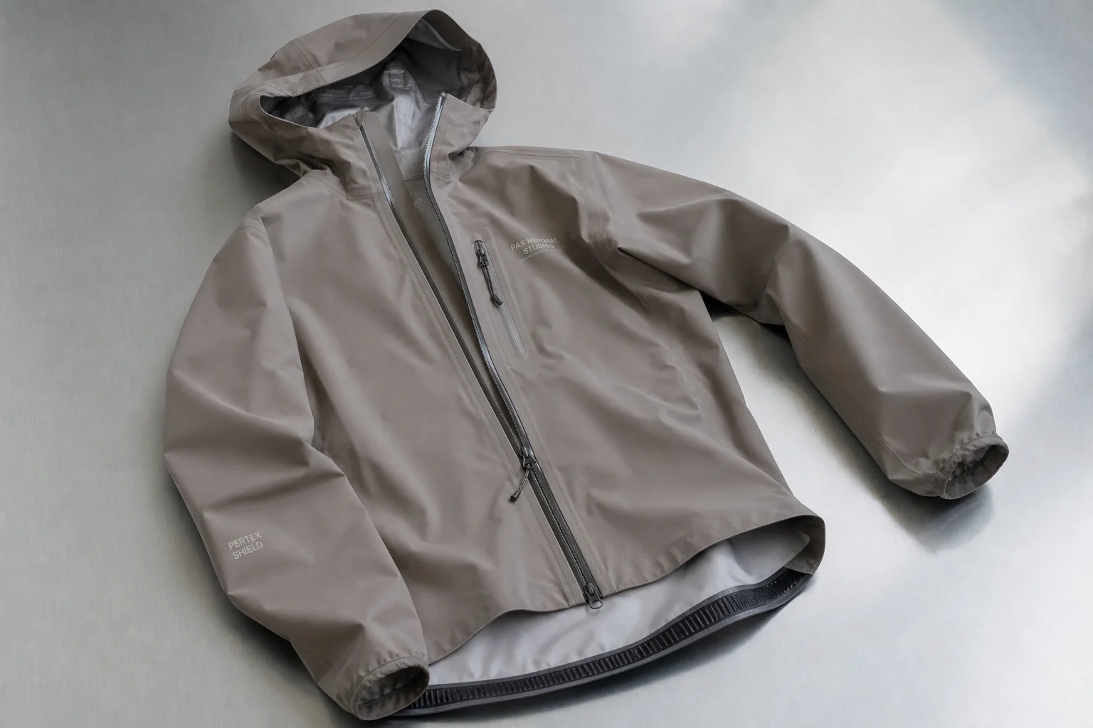 Cinq vestes de pluie pour le cyclisme de différentes couleurs disposées sur un fond neutre