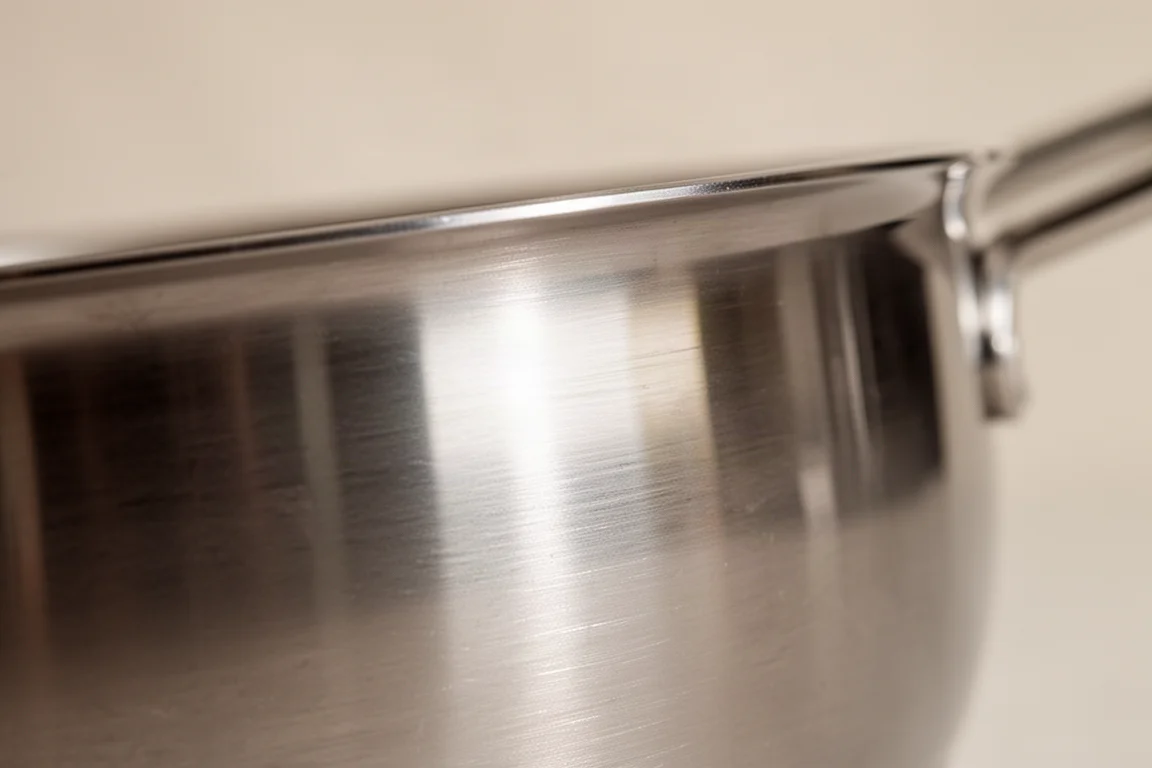 Close-up of a brushed stainless steel pan exterior showing subtle texture
