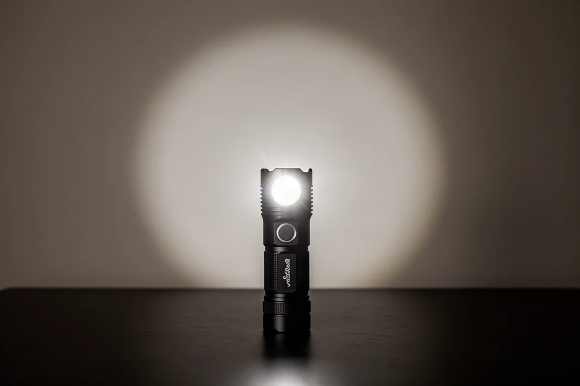 Small flashlight beam producing a bright central hotspot with wide spill in a dark room