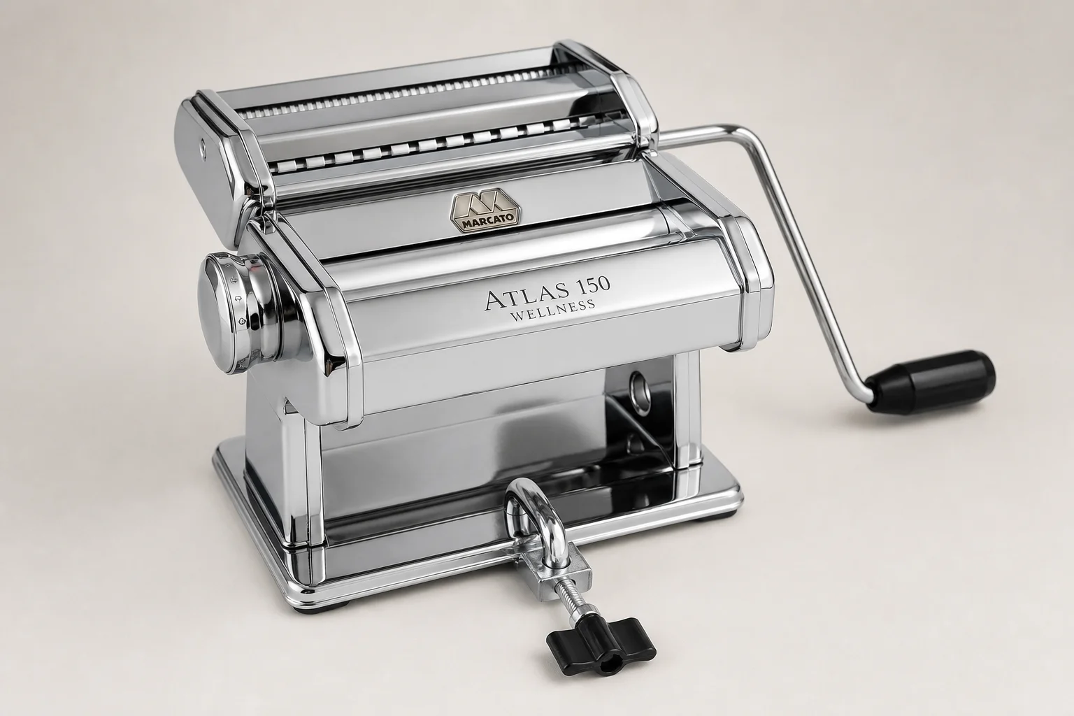 Five pasta makers arranged on wood surface including hand-crank and powered models