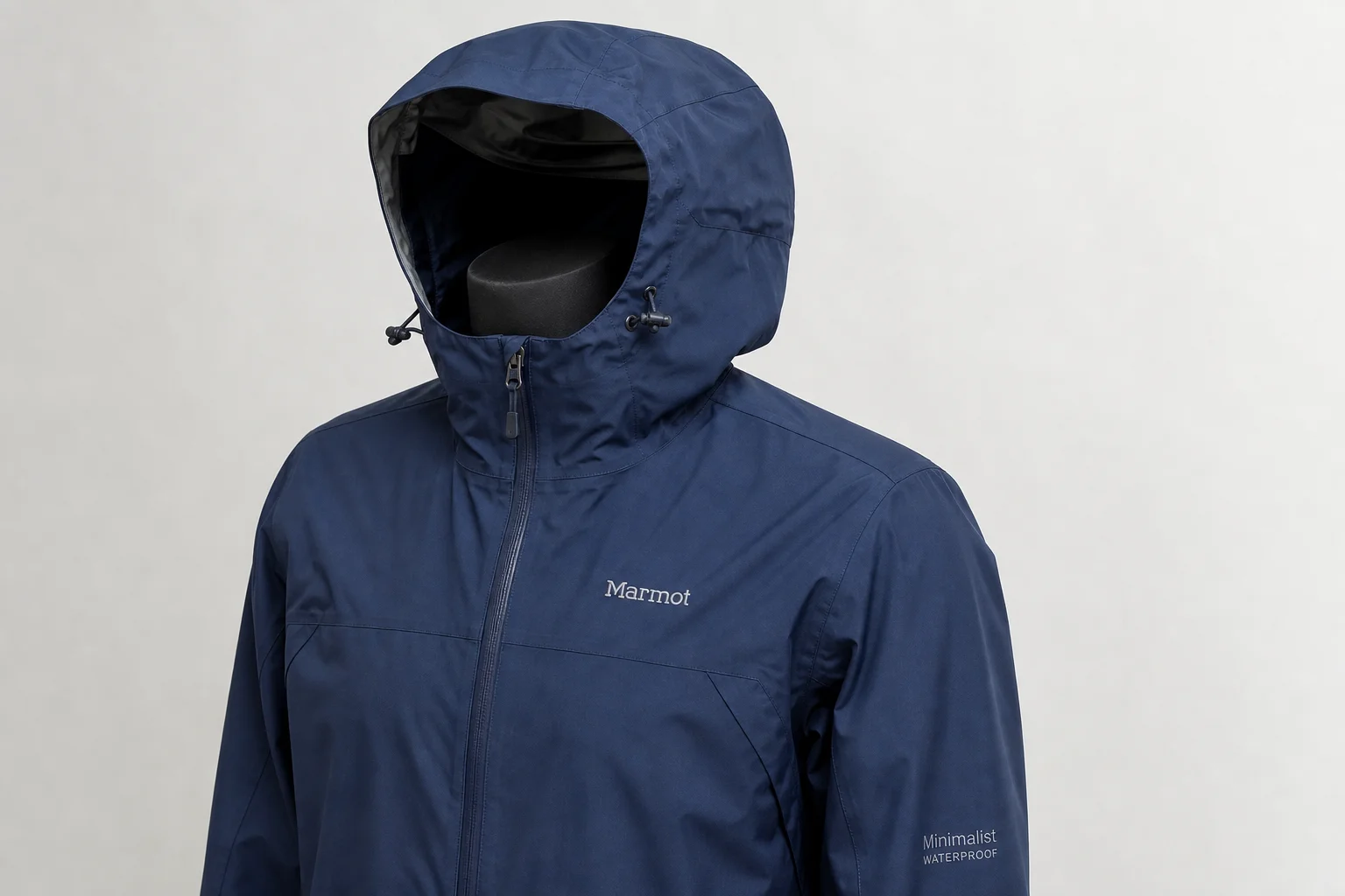 Cinco chaquetas impermeables de distintos colores y estilos dispuestas sobre hormigón