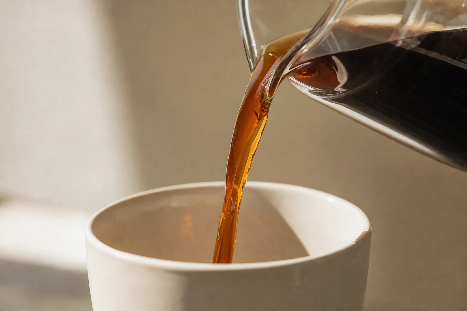 Cold brew coffee pouring smoothly into a white ceramic cup