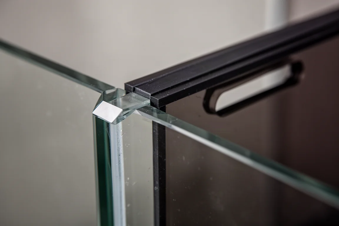 Close-up of beveled glass aquarium corner with black silicone seam and dark smoke rear panel
