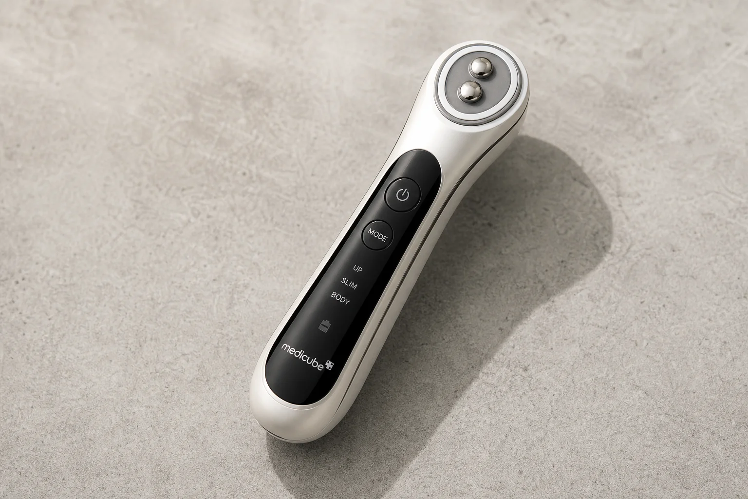 Five anti-aging devices arranged on concrete: gua sha stone, facial patches, microcurrent device, red light mask, and microneedling roller