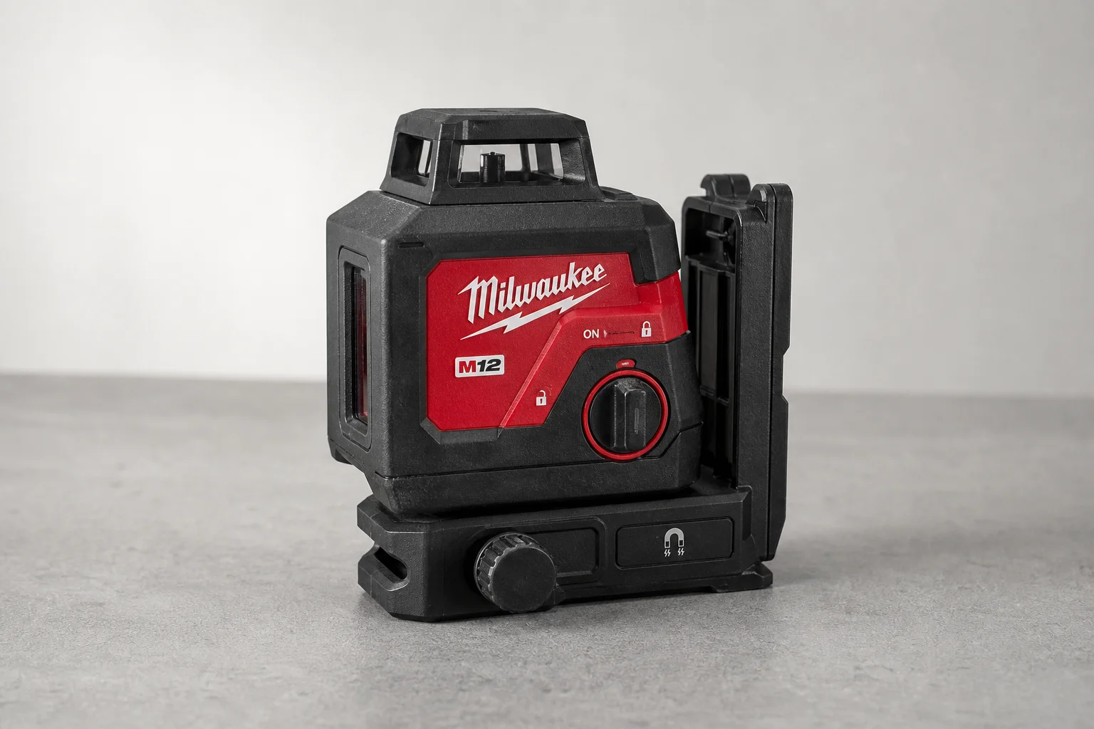 Milwaukee M12 fyrpunktslaser på en grå yta som visar basen och kontrollerna