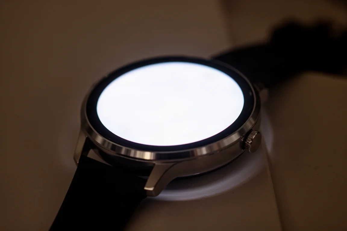 Tela do smartwatch brilhando intensamente em um ambiente escuro, exibindo um mostrador vibrante