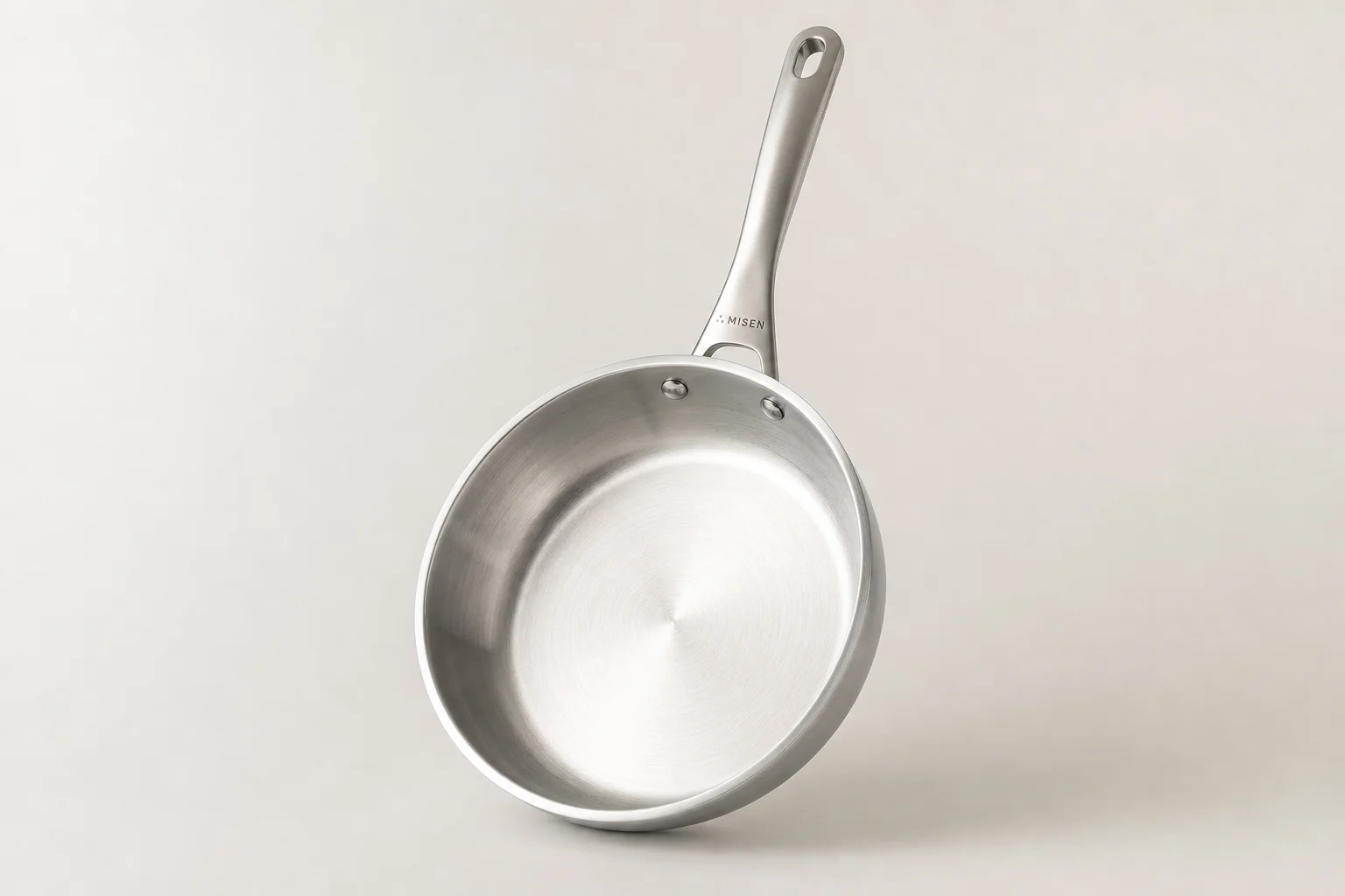 Five stainless steel pans arranged in a fan pattern on concrete surface