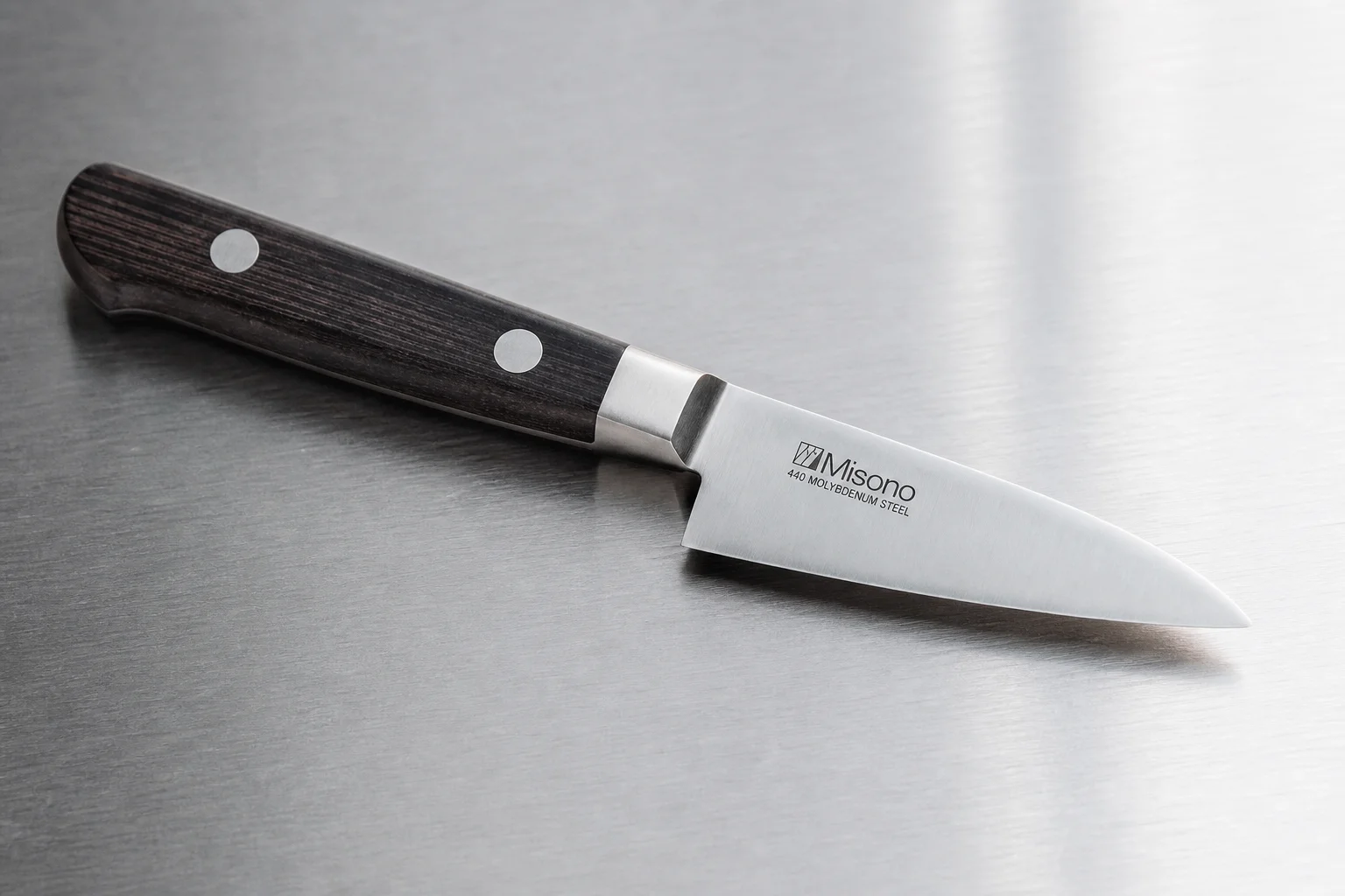 Professional kitchen knives and tools arranged on concrete surface