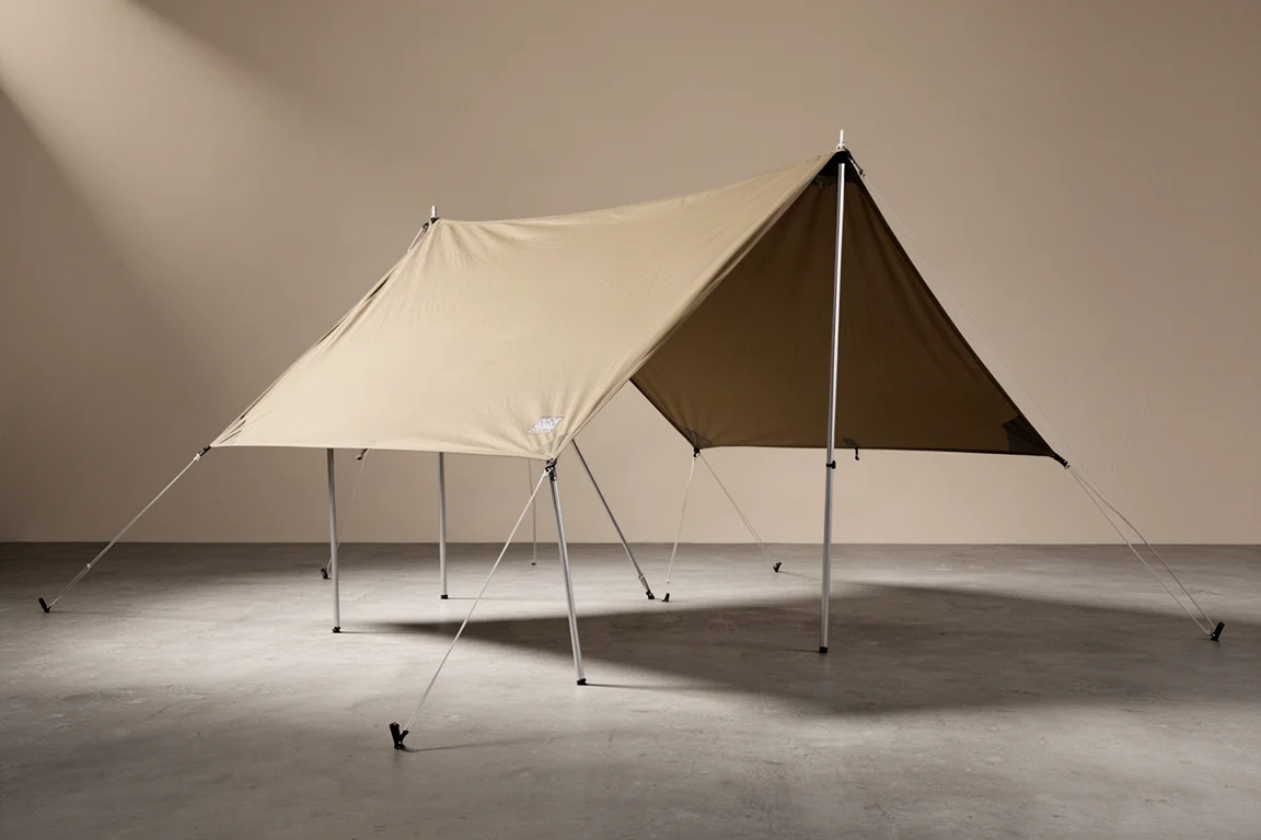 Light khaki gabled camping tarp awning pitched with aluminium poles on a concrete surface
