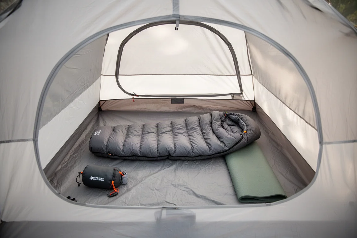 Sac de couchage et matériel de camping disposés à l'intérieur d'une tente spacieuse pour deux personnes