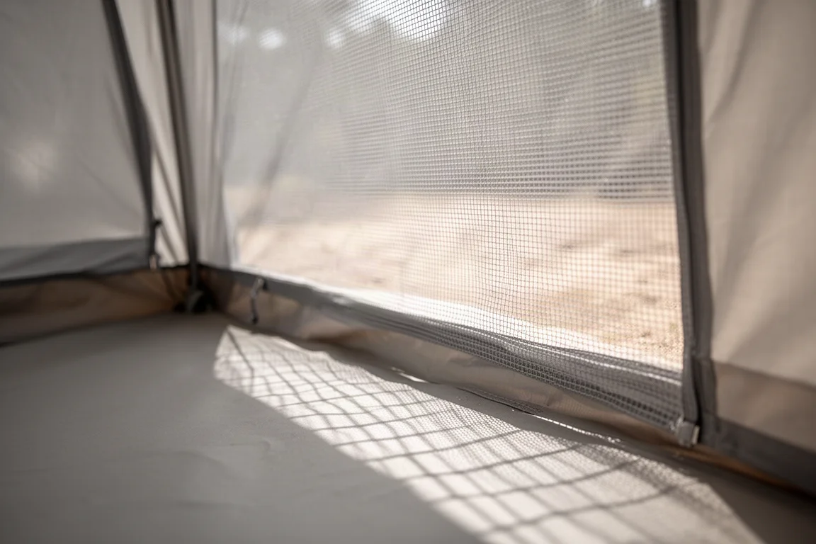 Interior view of a tent mesh wall with sunlight filtering through