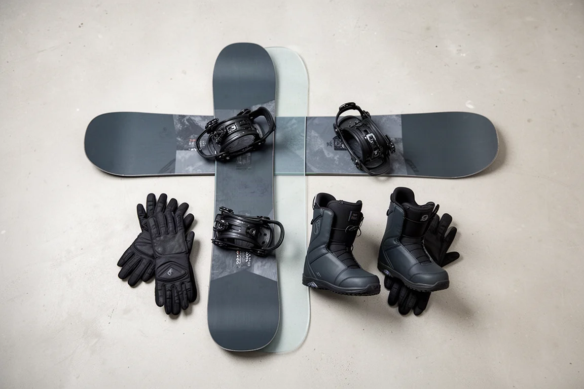 Snowboard mit Bindungen, Boots und Handschuhen von oben auf Beton drapiert